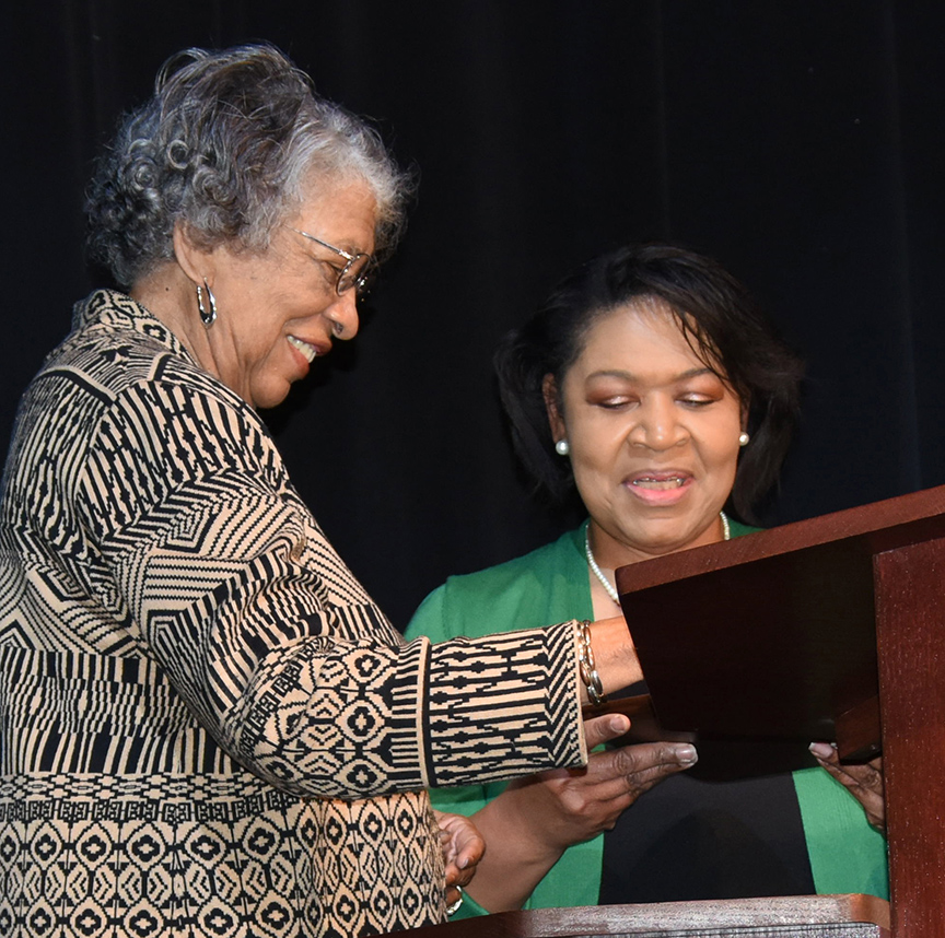 Melba Clark-Payne, left, greets Deborah Nettles, a member of the MLK Celebration Committee, at the lectern. Clark-Payne received the Billy C. Beal Award during the program. 