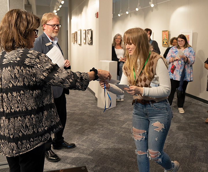 Angel Plott receives her medallion for winning first place in the drawing category. 