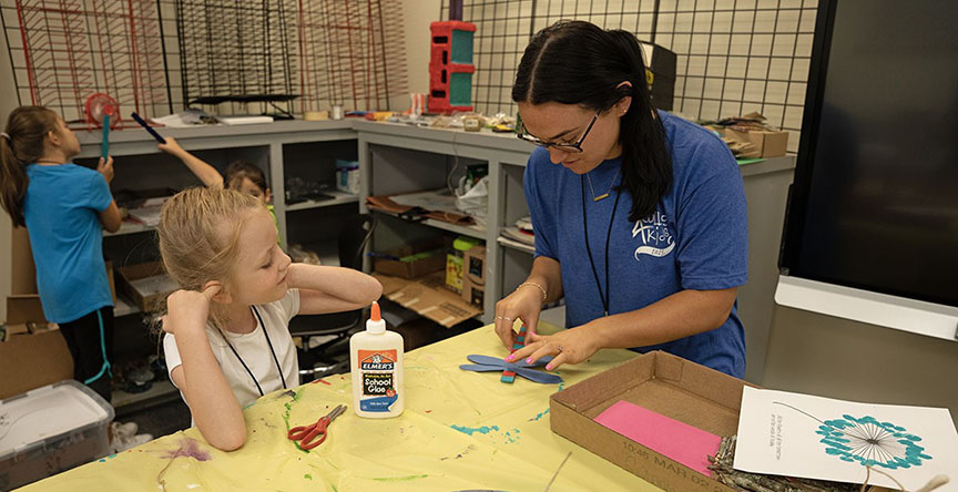 Alexis Crawford helps a College 4 Kids participant assemble a stick butterfly in the Fairies, Flora, and Fauna class. 