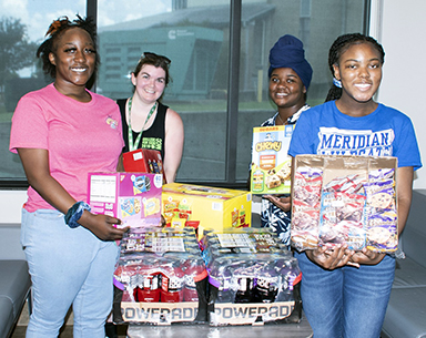 Nykiera Hill, front left, and Laneice Kincaide, front right, members of Meridian High School’s Color Guard Royal Dynasty, with Courtney Pitts, MCC’s College for Kids coordinator, back left, and Demetria Walker, sponsor of the MHS program. The high school group donated snacks for the volunteers for College for Kids. 
