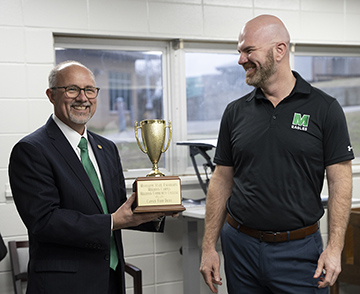 MCC President Dr. Tom Huebner, left, accepts the canned food drive competition from Mississippi State University-Meridian Associate Vice President and Head of Campus Dr. Terry Dale Cruse. 