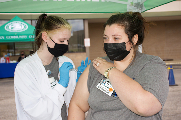 Camryn Brewer, left, gives fellow student Caroline Presley her first Pfizer vaccination during the College’s COVID-19 vaccination drive thru session. 