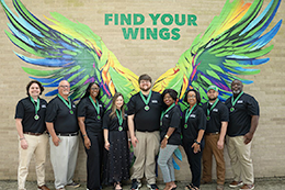The The Eagles Leadership Convocation (E.L.C.) Class of 2026 pose in front of a painted wall mural depicting colorful eagle wings and the phrase 