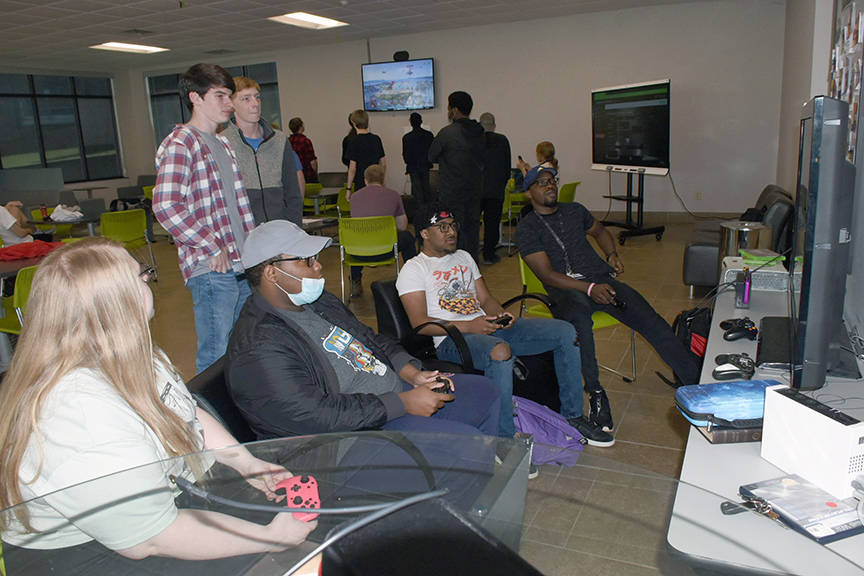 Tournament participants gather around two game monitors as they battle one another in the Eagle Esports competition.