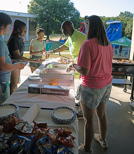 Student Affairs staffers serve burgers and hot dogs at the Campus Cookout Splash Edition.