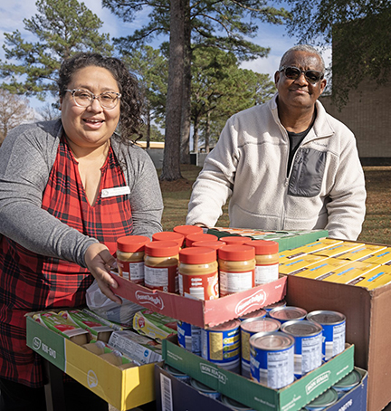 Wendy Cox, left, accepts the food donation spearheaded by Mark Thomas, right.