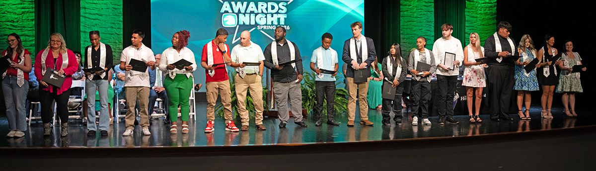 Meridian Community College students stand on stage holding certificates during the National Technical Honor Society Induction ceremony.