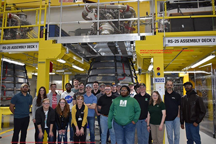 Meridian Community College students and faculty pose in front of one of the rockets at Aeroject Rocketdyne. 
